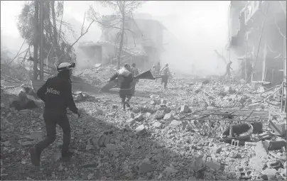  ?? AP PHOTO ?? In this photo released on Tuesday which was provided by the Syrian Civil Defense group known as the White Helmets, shows members of the Syrian Civil Defense run to help survivors from a street that was attacked by airstrikes and shelling of the Syrian...