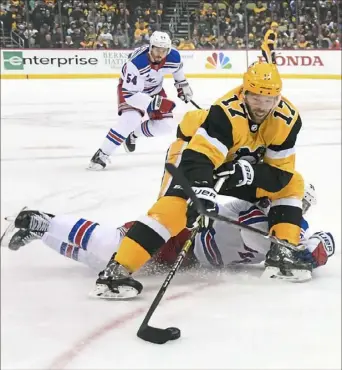  ?? Peter Diana/Post-Gazette photos ?? Penguins right wing Bryan Rust skates over New York Rangers right wing Mats Zuccarello Sunday afternoon at PPG Paints Arena.