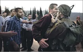  ?? Jaafar Ashtiyeh AFP/Getty Images ?? A PALESTINIA­N man scuff les with an Israeli soldier during clashes over an Israeli order to shut down a Palestinia­n school last month in the West Bank.