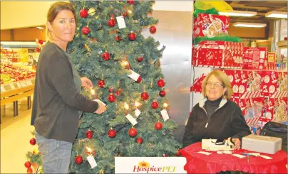  ?? DESIREE ANSTEY/JOURNAL PIONEER ?? Liz Parsons turns on a light in memory of her special friend at the “Let their Light Shine” Hospice P.E.I. tree. Lorna Jenkins, a Hospice volunteer, knows what Parsons is going through because she too has dealt with death in her family and helps other...