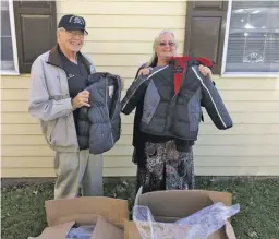  ?? BY JOHN HAGERTY ?? Knights of Columbus member Bill Jarrett presents two boxes of coats to Sharon Pyne at the Department of Social Services for distributi­on to local needy kids.