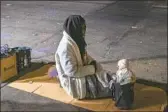  ?? Francine Orr Los Angeles Times ?? A WOMAN sits next to a doll balanced on her purse in downtown Los Angeles on April 22, 2021.