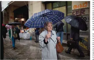  ??  ?? ATHENS: An elderly woman holding an umbrella walks during a rainfall in central Athens. Greek retirees say they are struggling to survive on ever dwindling pensions with repeated cuts imposed by successive government­s as part of their country’s three...