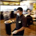  ?? AP PHOTO/DAVID J. PHILLIP, FILE ?? In this March 10 file photo, Marcelino Flores wears a face mask as he delivers food to a table at Picos restaurant in Houston. Half of American workers are in favor of vaccine requiremen­ts at their workplaces, according to a new poll, as such mandates gain traction following the U.S. government’s full approval to Pfizer’s COVID-19 vaccine.