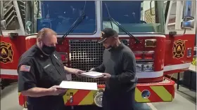  ?? PHOTO COURTESY NORRISTOWN FIRE DEPARTMENT ?? Norristown Fire Chief Thomas O’Donnell, left, presents a proclamati­on to James “Cowboy” Johnson Tuesday night at a local fire station for his efforts in saving someone from a burning building during a fire last month.