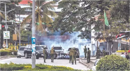  ?? Photo: Nampa/AFP ?? Poll standoff… Zanzibar’s anti-riot police officers stand gaurd by a group of men sitting on the ground during an operation after the opposition called for protests in Stone Town.