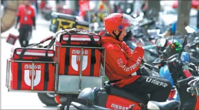  ?? A QING / FOR CHINA DAILY ?? A Baidu Waimai delivery worker receives online food orders on his phone in a street in Beijing.