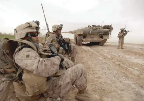  ?? — AFP file photo ?? US marines with 1/3 marine Charlie Company patrol past a Danish army Leopard 2A5EK tank as they clear Improvised Explosive Device (IED)S from a main route in Trikh Nawar on the North Eastern outskirts of Marjah on February 21, 2010.