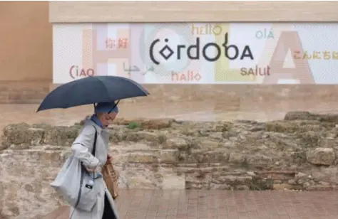  ?? // VALERIO MERINO ?? Una turista pasa con su paraguas junto a la oficina de turismo de la ciudad en la Puerta del Puente