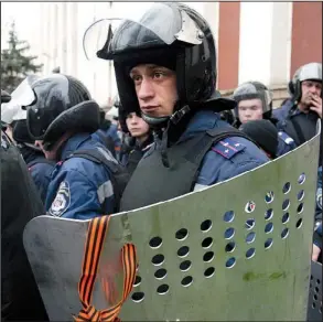  ?? AP/ALEXANDER ERMOCHENKO ?? Men wearing uniforms of Ukraine’s disbanded riot police stand guard Saturday outside a regional
police building in Donetsk in eastern Ukraine.