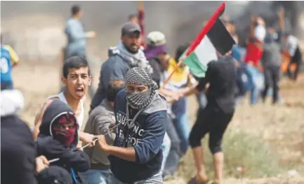  ?? Khalil Hamra, The Associated Press ?? Palestinia­n protesters try to pull apart a fence placed by the Israeli army during a protest at the Gaza Strip’s border with Israel on Friday.