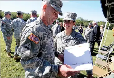  ?? NWA Media/J.T. WAMPLER ?? Brig. Gen. Patricia Anslow (right) gives a binder filled with command strategies, guidance and advice to Col. Gregory Bacon on Saturday. Bacon assumed command of the 142nd Field Artillery Brigade from outgoing commander Col. Troy Galloway.