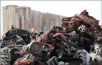  ??  ?? The remains of destroyed and burned cars are seen Wednesday in front of towering grain silos that were gutted in the massive August 2020 explosion.