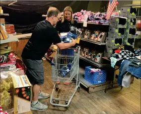  ?? RECORDER PHOTO BY ESTHER AVILA ?? PACC Executive Director Ryan Land helps Port Naz’s Shelby Thompson fill a grocery cart with socks and underwear and other essentials. PACC has donated numerous items to the Dixie Project for the victims of the Dixie Fire in Northern California.