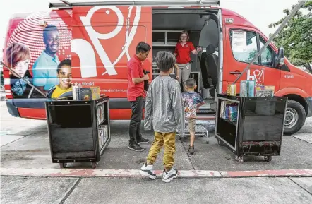  ?? Steve Gonzales photos / Staff photograph­er ?? Luis Cerna and Rachel Stout welcome Second Ward children to the Houston Public Library’s Mobile Express bookmobile earlier this month. The Flores Neighborho­od Library is one of the branches that has been closed since Harvey slammed the area.