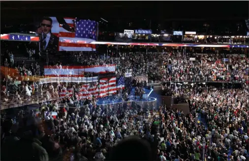  ?? The Associated Press ?? CLOSE LOOK: In this July 26, 2016, file photo, the stage is reflected on a glass window on the suite level at Wells Fargo Arena as Timmy Kelly sings the national anthem before the start of the second day session of the Democratic National Convention in Philadelph­ia. The coronaviru­s pandemic is forcing Democrats and Republican­s to take a close look at whether they’ll be able to move forward as planned this summer with convention­s that typically kick off the general election season.