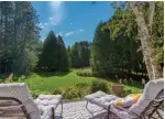  ??  ?? The large backyard features a patio, garden beds, a firepit a large lawn and trails through a forested area.