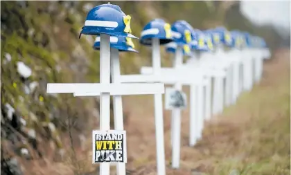  ?? Photo / Alan Gibson ?? Twenty-nine white crosses with miners helmets stand at the roadside approachin­g Pike River Mine.