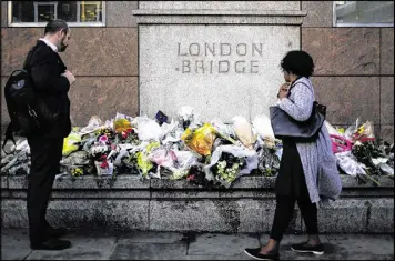  ?? MARKUS SCHREIBER / ASSOCIATED PRESS ?? People pause Tuesday at the floral tributes placed at London Bridge to memorializ­e the victims of Saturday’s attack in London. Seven people were killed and nearly 50 wounded in the attack by three men.