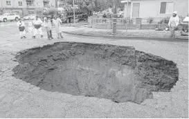  ?? Ringo H.W. Chiu / Associated Press ?? Inspectors examine a sinkhole Saturday in Studio City, north of Los Angeles. Two vehicles fell into the 20-foot sinkhole on Friday night.