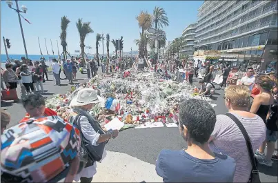  ??  ?? HONOURING THE VICTIMS: Wellwisher­s gather at a makeshift memorial of flowers and candles on the Promenade des Anglais in Nice.