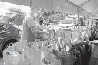  ?? MIKE STOCKER/SOUTH FLORIDA SUN SENTINEL ?? Volunteers pack bags with kosher food at the Jewish Federation of Broward County in Davie on Thursday.