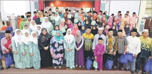  ??  ?? Jamilah (front, seventh left), with Rubiah on her right, joins a photo-call with members of Perkim Kota Samarahan and recipients of the Raya contributi­ons.