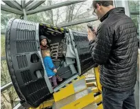  ??  ?? Michael Finkler of Berkeley takes a photo of his children, Nathaniel, 5, and Uma, 2, as they climb in a hands-on display at the Chabot Space & Science Center for fans of space exploratio­n.