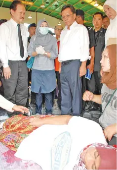  ??  ?? Azizah taking care of her mother Rema, as Shafie (third left) and Stephen (left) visit the fire victims at the Likas community hall yesterday.