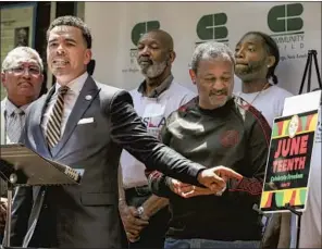  ?? Irfan Khan Los Angeles Times ?? THE REV. Shane Harris, center, f lanked by other civil rights activists in L.A., urges President Biden on Thursday to sign a bill into law making Juneteenth a federal holiday.