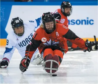  ?? - Associated Press: Joel Marklund ?? Adam Dixon, du Canada, transporte la rondelle devant un joueur sud-coréen en demi-finale de parahockey, jeudi.