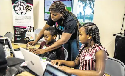  ?? PEDRO PORTAL pportal@miamiheral­d.com ?? Anike Sakariyawo, CEO and founder of the S.E.E.K Foundation, works with Kinsley (left) and Keymaree Michaud, during a STEAMtasti­c Saturday in Miami Gardens, where kids learn about science, tech, math, engineerin­g and art.