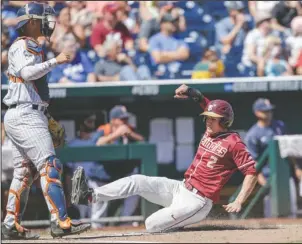  ?? The Associated Press ?? MOVING ON: Florida State’s Jackson Lueck (2) scores at home plate on a single by Matt Henderson, as Cal State Fullerton catcher Chris Hudgins waits for the throw in the seventh inning of a College World Series game in Omaha, Neb., Monday.