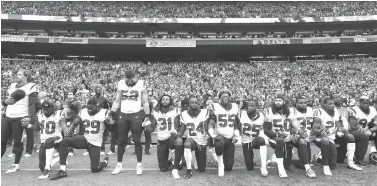  ?? Elaine Thompson/Associated Press file photo ?? ■ Houston Texans players kneel and stand during the singing of the national anthem before an NFL game on Oct. 29, 2017, against the Seattle Seahawks, in Seattle. The NFL Players Associatio­n filed a grievance with the league challengin­g its national...