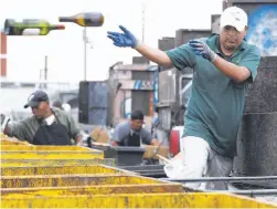  ??  ?? A man tosses wine bottles into large bins at the Our Top: Customers line up to have goods weighed before they receive a cash payment at a collection center on Bayshore Boulevard. Above: A customer tosses wine bottles into a bin at the center.