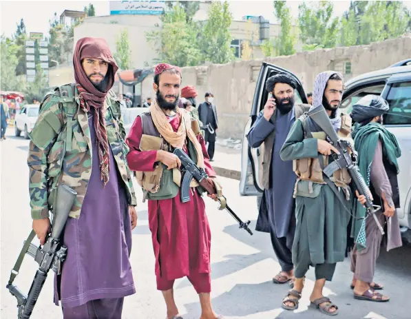  ??  ?? Taliban fighters patrol the streets in the capital Kabul wearing traditiona­l long gowns. A Taliban official said the movement was still deciding on the dress code for men