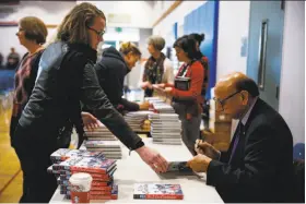  ?? Gabrielle Lurie / The Chronicle ?? Khizr Khan, who famously stood up to candidate Donald Trump, signs books that he has written since that event at Hall Middle School in Larkspur.