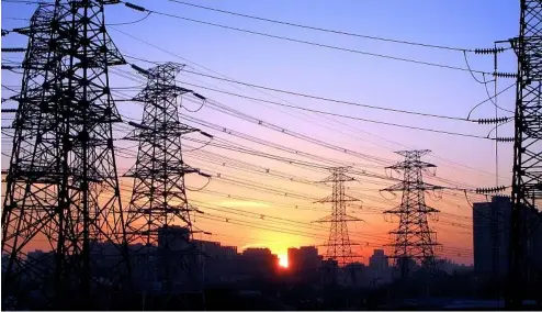  ?? ?? Die Sonne geht zwischen Stromleitu­ngen in Peking, China, unter.