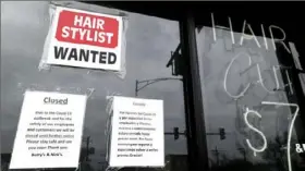  ?? Nam Y. Huh/ Associated Press ?? A barber shop in Chicago displays closed and hiring signs during the early months of the COVID- 19 pandemic.