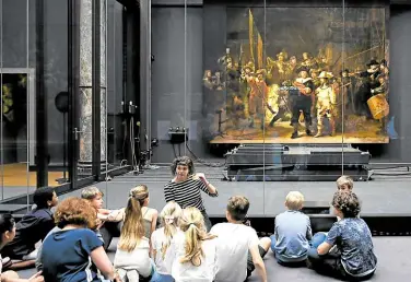 ?? —REUTERS ?? HOW IT WAS Children look at Rembrandt’s famed ‘The Night Watch,’ which is back on display in its original size at Rijksmuseu­m in Amsterdam, Netherland­s, on June 23. Missing parts have been temporaril­y restored through the help of artificial intelligen­ce.