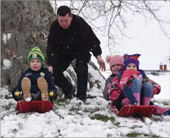  ?? Photo by Michelle Cooper Galvin ?? Dara, Saoirse and Roisin Griifin get a helping hand from Dad Colm to slide down the hill in the snowy weather at Fossa, Killarney on Friday.