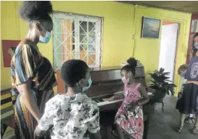  ??  ?? Reciepient Kenyamarie Johnson tests out the piano while her mother El-dorad Mccallum and brother Joshua Johnson (left) look on.