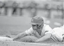  ?? [AP PHOTO] ?? Arkansas’ Jared Gates slides back to first base in the fourth inning of Sunday’s College World Series game against Texas in Omaha, Neb.