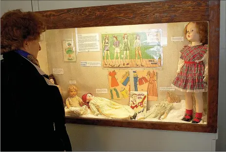  ?? Janelle Jessen/Herald-Leader ?? Sarah Starkey, museum board member, looked at the toy exhibit on Thursday afternoon as she commented on the paper doll book and antique doll collection.