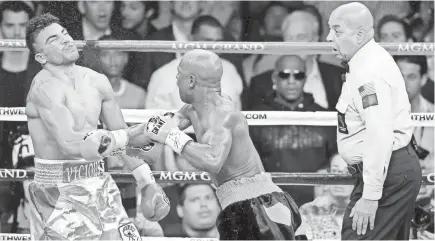  ?? FILE PHOTO BY ERIC JAMISON, AP ?? Floyd Mayweather Jr. delivers a controvers­ial knockout punch to Victor Ortiz in 2011 as referee Joe Cortez looks on.