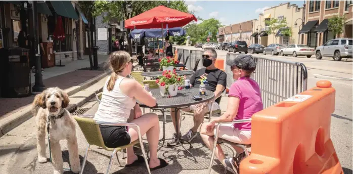  ?? RICH HEIN/SUN-TIMES ?? Diners outside Empire restaurant in Naperville Friday afternoon. Many Naperville restaurant­s expanded their sidewalk dining areas by barricadin­g a portion of street parking spots outside.