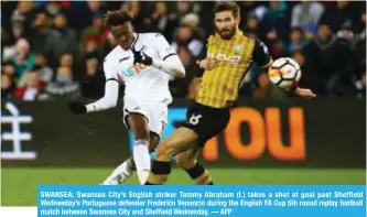  ?? — AFP ?? SWANSEA: Swansea City’s English striker Tammy Abraham (L) takes a shot at goal past Sheffield Wednesday’s Portuguese defender Frederico Venancio during the English FA Cup 5th round replay football match between Swansea City and Sheffield Wednesday.