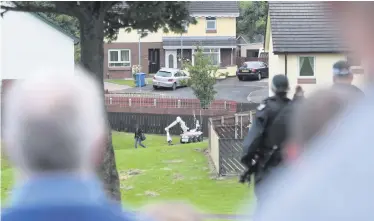  ??  ?? Concerned police call out a warning as a woman walks past the robot dealing with the suspect device in Galliagh