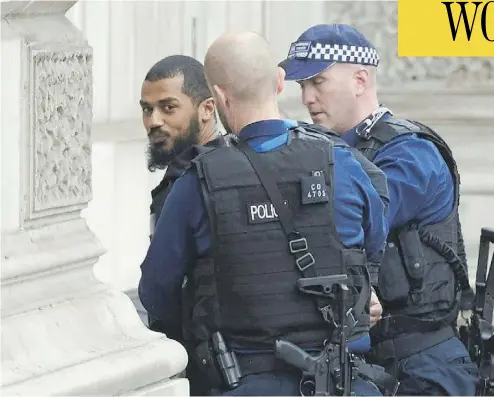  ?? NIKLAS HALLE’N / AFP / GETTY IMAGES ?? British police officers detain a man near Downing Street and the houses of Parliament in central London on Thursday. The man, who was under surveillan­ce after a tip from his family, was carrying a number of knives.