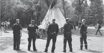  ?? TROY FLEECE/FILES ?? Members of the Regina Police Service stood by on June 18 in Wascana Centre as the initial teepee at the Justice For Our Stolen Children camp was dismantled.